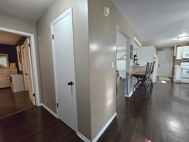 a view of a hallway with wooden floor table and chairs