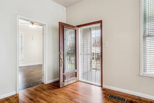 a view of an empty room with wooden floor and a window