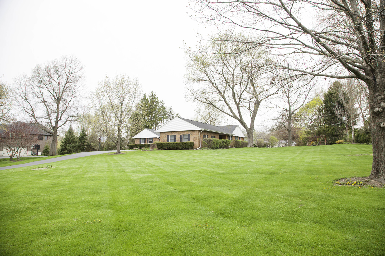 1630 Dunbar Road Inverness, IL 60067 - Photo 3 of 8 a yellow house with a big yard and large trees