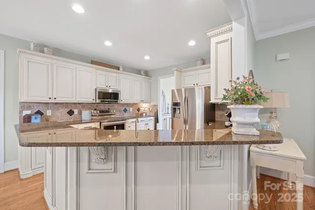 a kitchen with granite countertop white cabinets and refrigerator