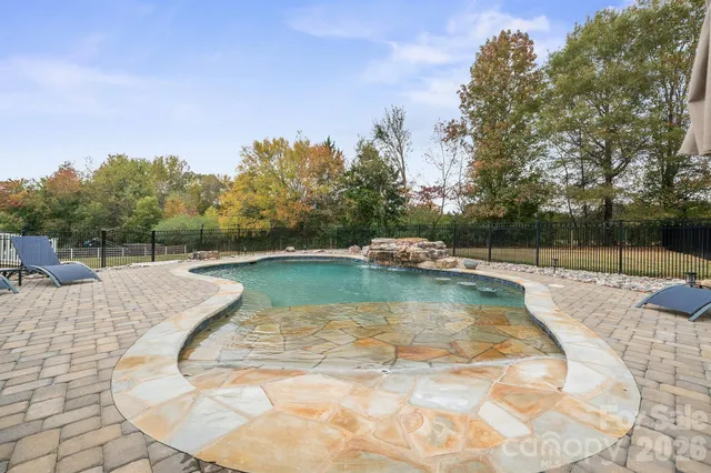 a view of a swimming pool with a lounge chairs in front of house