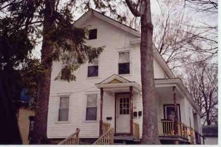 a view of a white house with large tree front of house