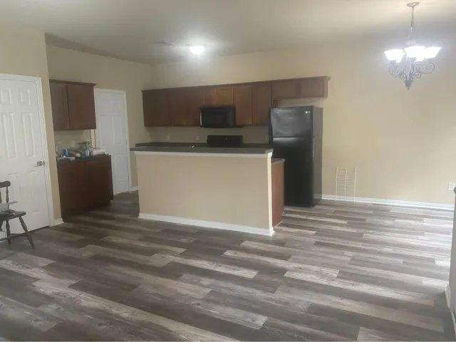 a view of kitchen and empty room with wooden floor