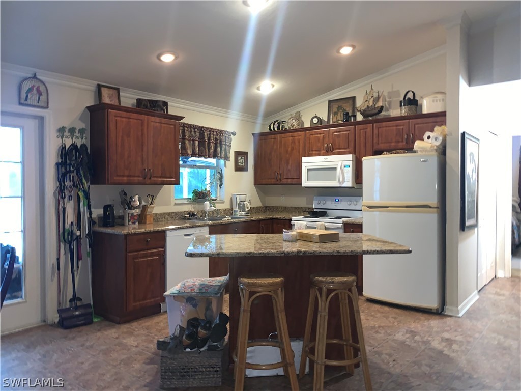 18599 Flamingo Road Fort Myers, FL 33967 - Photo 12 of 30 a kitchen with stainless steel appliances granite countertop a stove refrigerator sink and cabinets