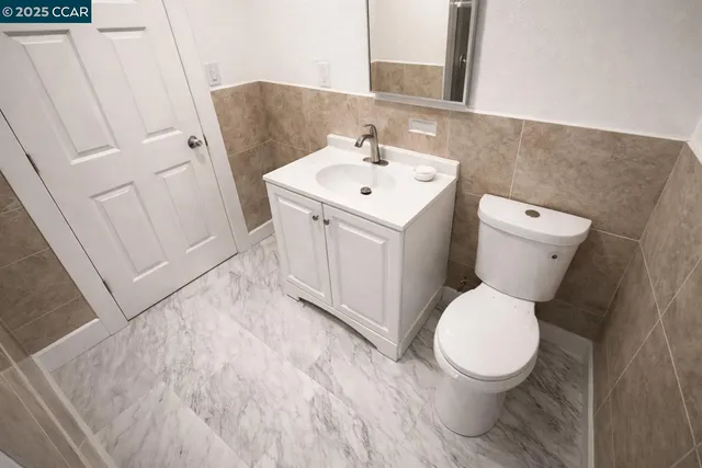 a white toilet sitting next to a white sink and vanity