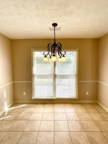 an empty room with wooden floor a ceiling fan a fireplace and windows