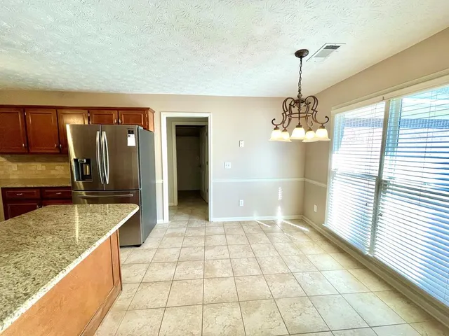 an empty room with wooden floor chandelier fan and windows