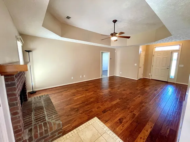 an empty room with wooden floor and fan