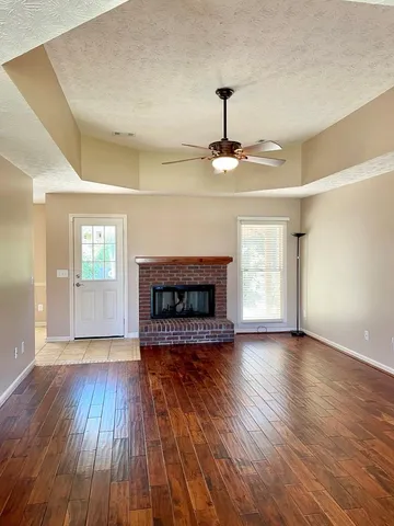 a view of an empty room with wooden floor fireplace and a window