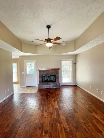 a view of a livingroom with a ceiling fan fireplace and wooden floor