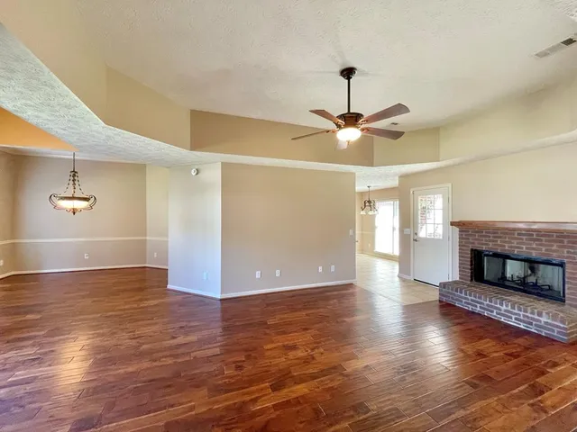 a view of a room with wooden floor ceiling fan and window