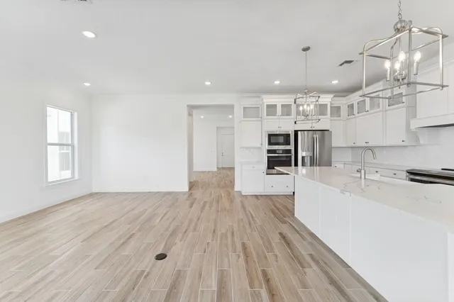 a large kitchen with kitchen island a stove a sink a refrigerator and a wooden floor