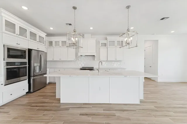 a kitchen with granite countertop white cabinets and stainless steel appliances