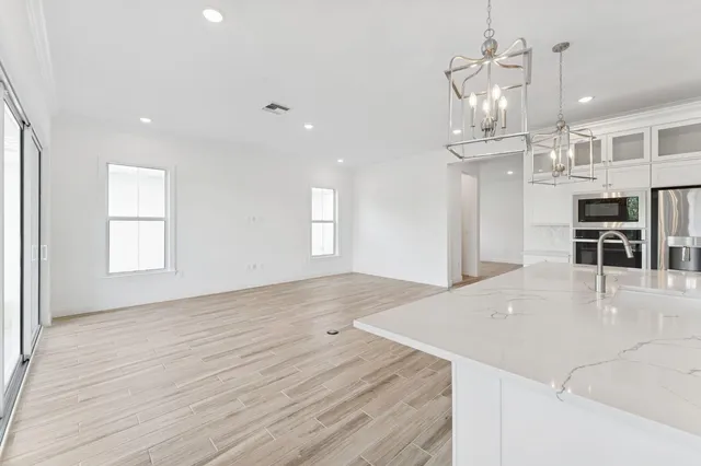 a large white kitchen with wooden floors and view living room