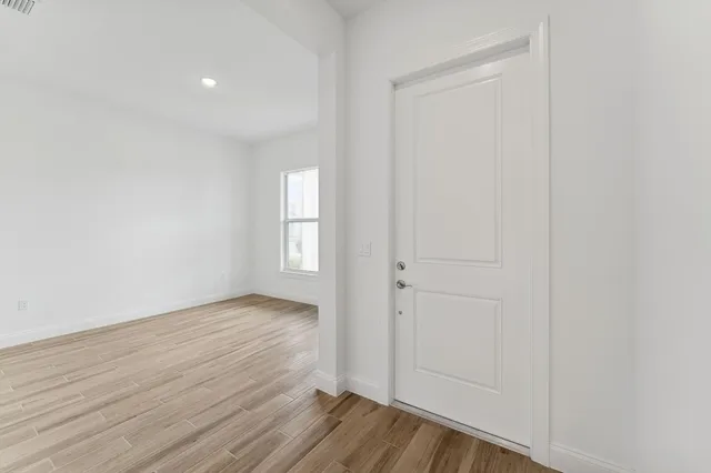 a view of an empty room with wooden floor and closet