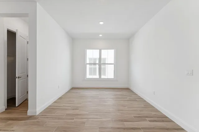 a view of an empty room with wooden floor and a window