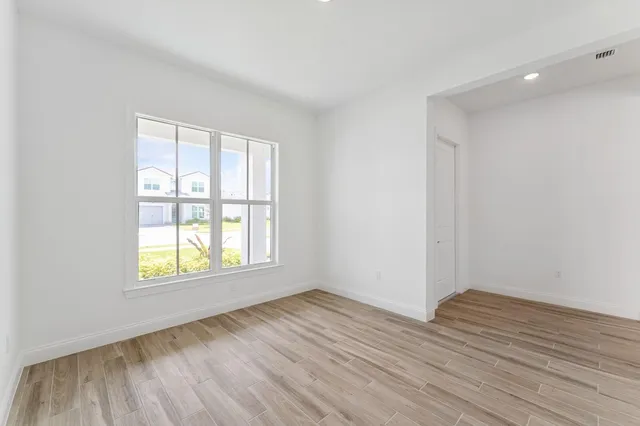 an empty room with wooden floor and windows