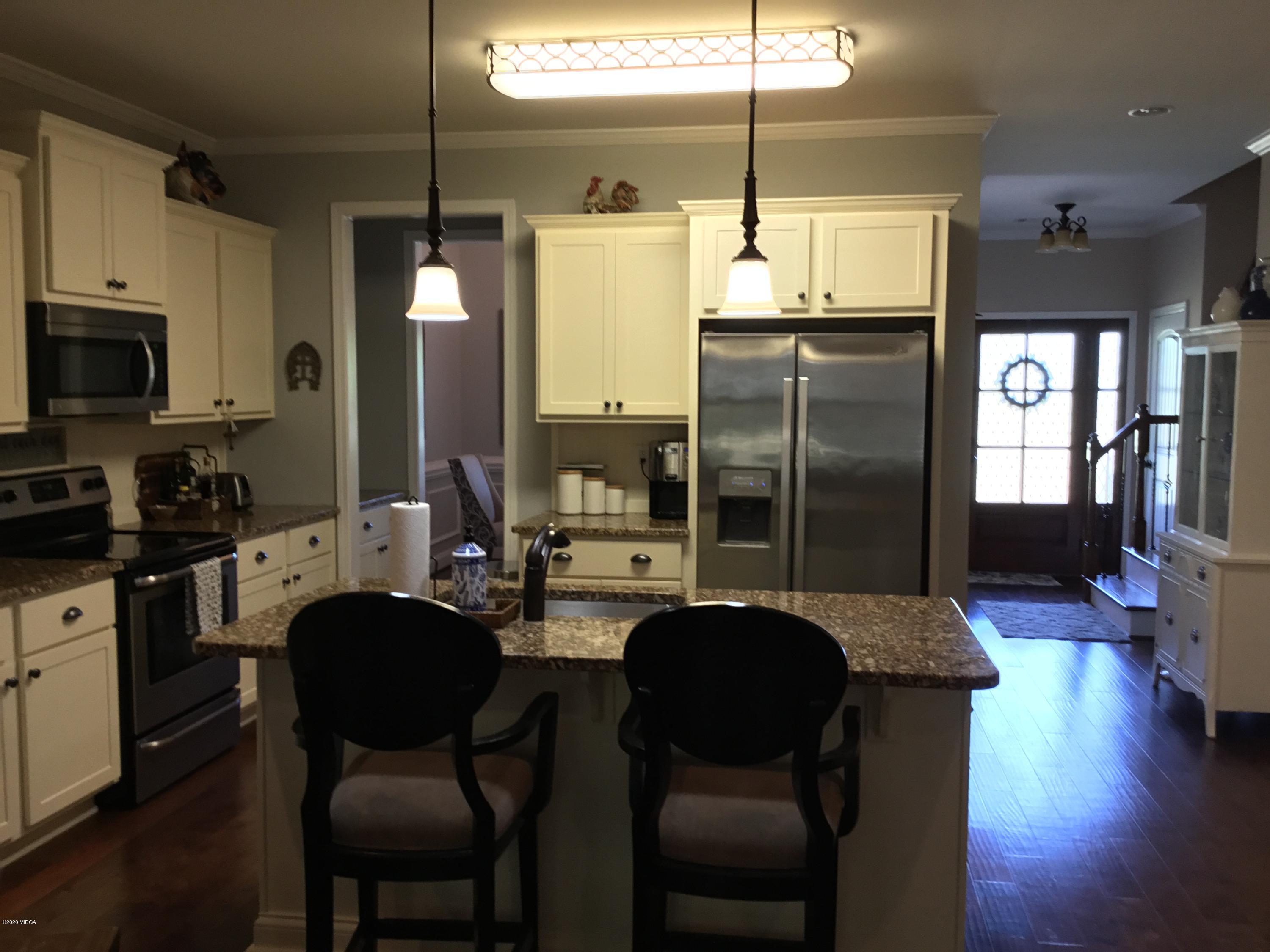 324 Walnut Grove Road Gray, GA 31032 - Photo 11 of 37 a kitchen with stainless steel appliances kitchen island granite countertop a refrigerator a stove a sink a dining table and chairs with wooden floor