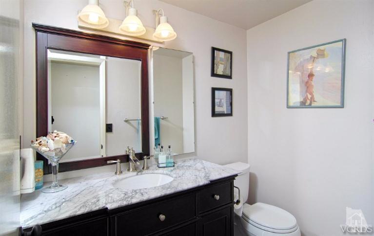 256 Kanan Road Oak Park, CA 91377 - Photo 18 of 26 a bathroom with a granite countertop sink vanity mirror and toilet