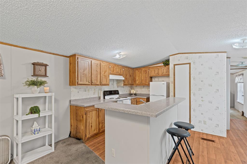 167 Hcr 4105 Covington, TX 76636 - Photo 18 of 32 Kitchen with white appliances, vaulted ceiling, light wood-type flooring, light countertops, and a kitchen island