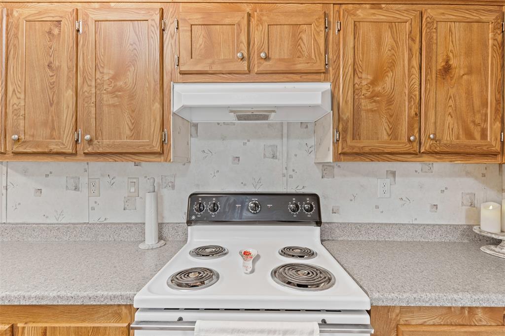 167 Hcr 4105 Covington, TX 76636 - Photo 22 of 32 Kitchen with white range with electric stovetop, exhaust hood, and light countertops