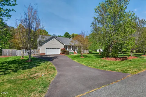 a view of a house with a big yard and large trees