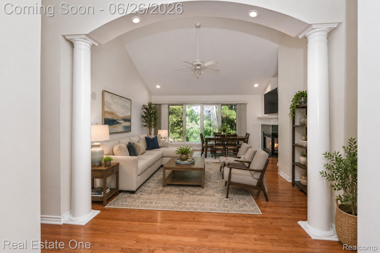 227 Bloomer Ridge Court Rochester, MI 48307 - Photo 4 of 45 Vaulted living area featuring an arched entryway with decorative columns, wood-finish flooring, and a fireplace with a white mantel