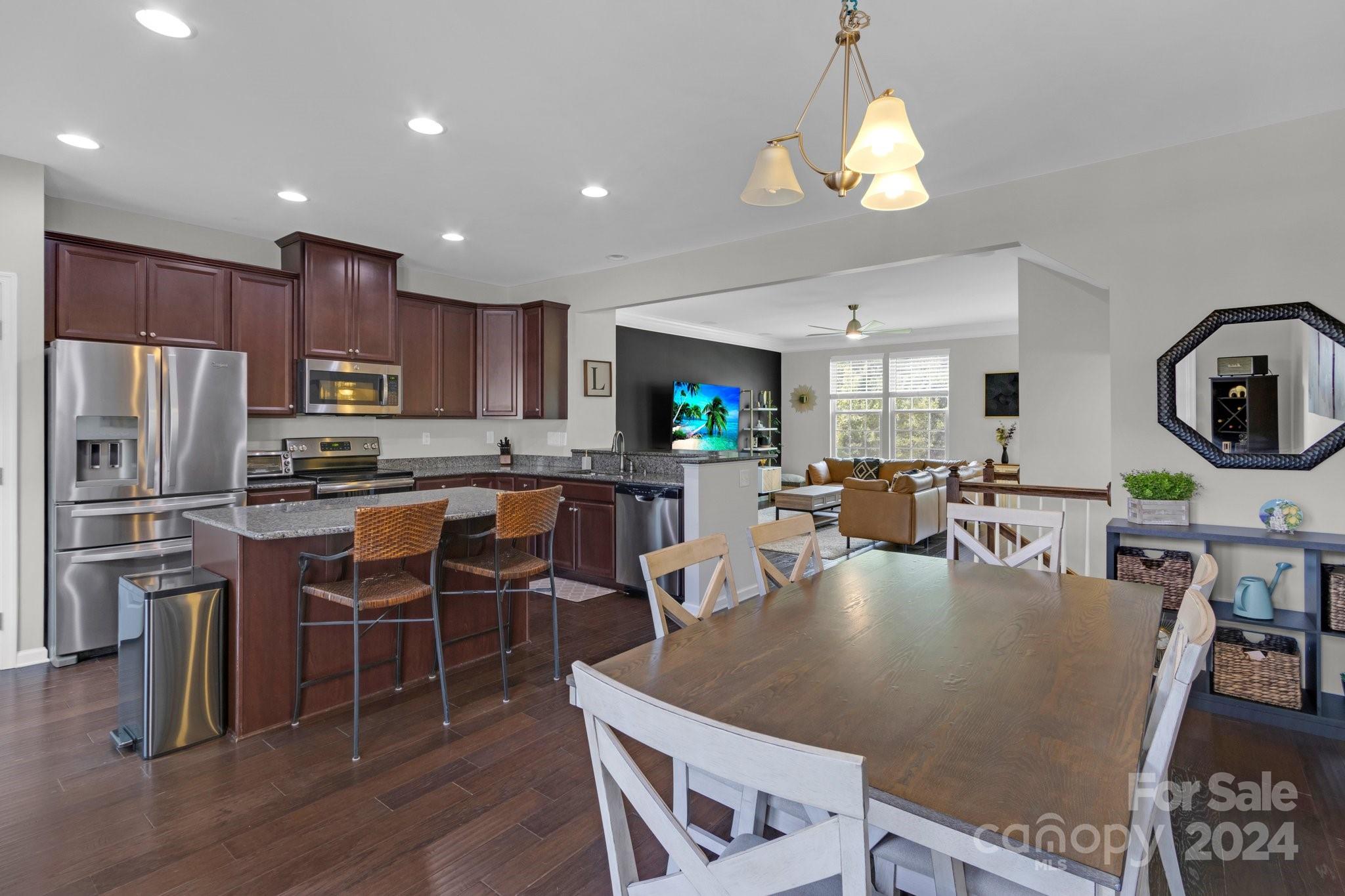 4012 Zilker Park Drive Charlotte, NC 28217 - Photo 8 of 31 a kitchen with stainless steel appliances granite countertop a stove top oven a refrigerator a sink dishwasher a dining table and chairs with wooden floor
