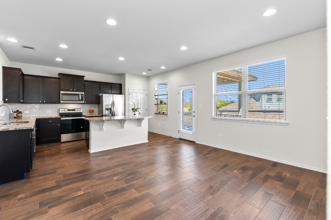 704 Coltrane Drive Pflugerville, TX 78660 - Photo 13 of 39 a view of kitchen with kitchen island microwave and wooden floor
