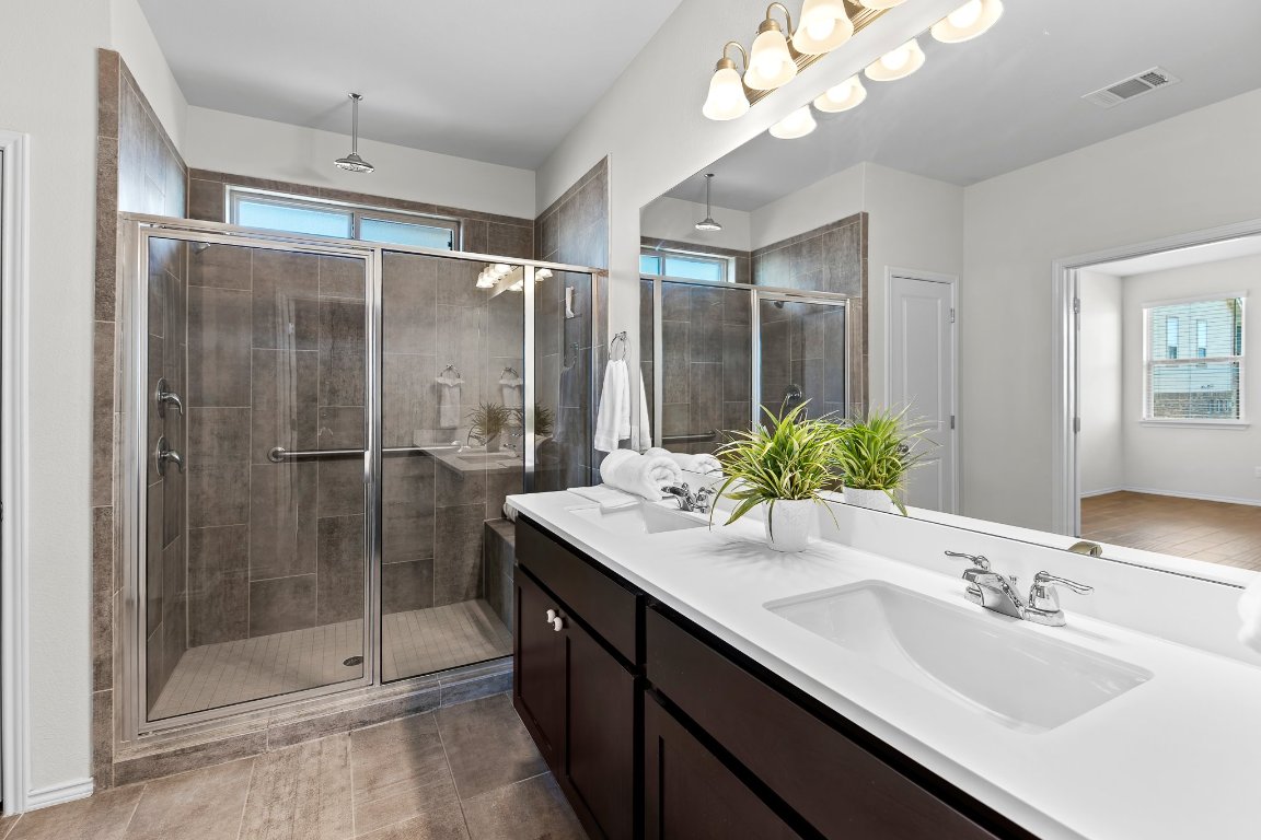704 Coltrane Drive Pflugerville, TX 78660 - Photo 26 of 39 a bathroom with a shower sink vanity granite and mirror
