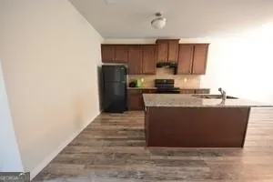 a room with kitchen island a sink wooden floor and a refrigerator