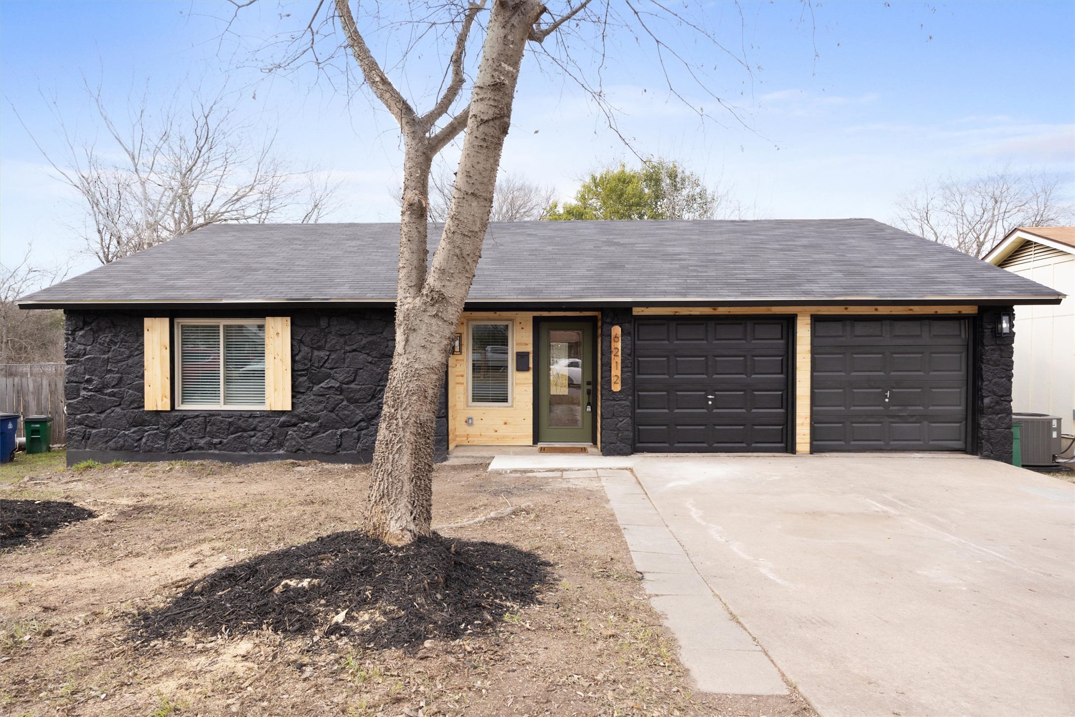 Ranch-style house featuring stone siding, concrete driveway, a shingled roof, and an attached garage