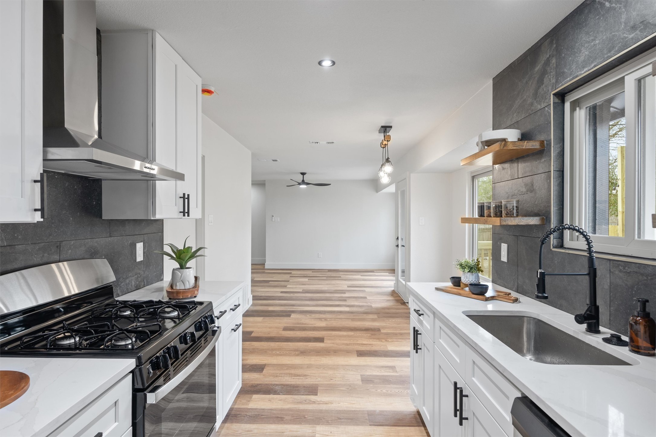 6212 Boxcar Run Austin, TX 78745 - Photo 14 of 36 Kitchen featuring stainless steel gas range oven, open shelves, white cabinets, light stone countertops, and backsplash