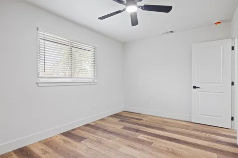 an empty room with a window and a ceiling fan