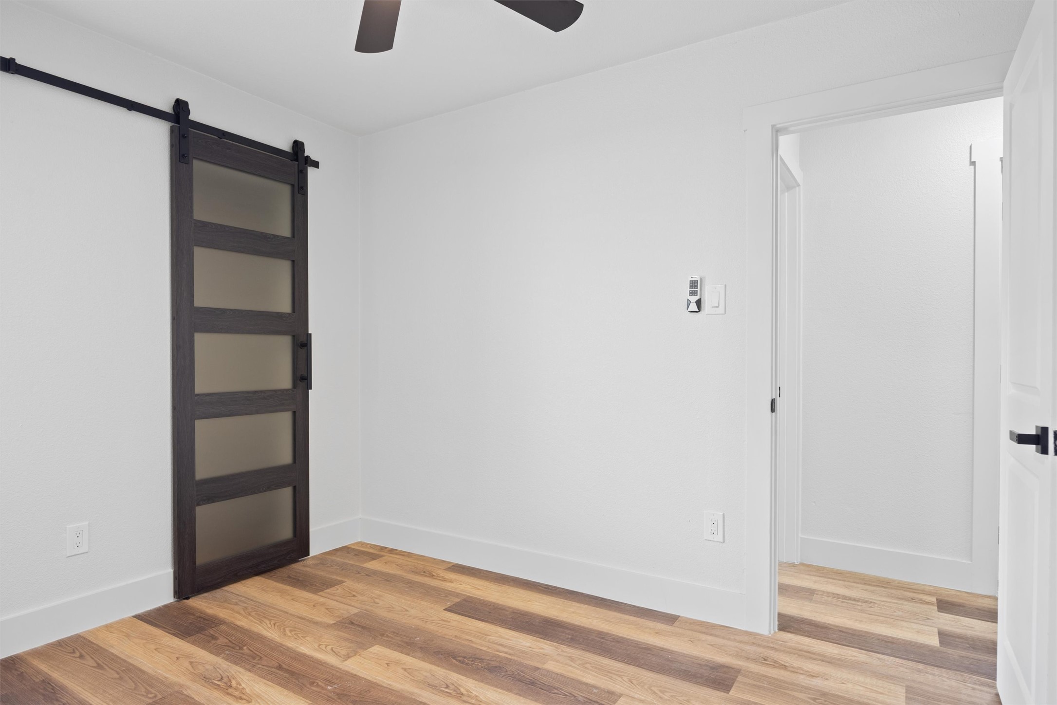 6212 Boxcar Run Austin, TX 78745 - Photo 26 of 36 Empty room with a barn door, light wood finished floors, and a ceiling fan