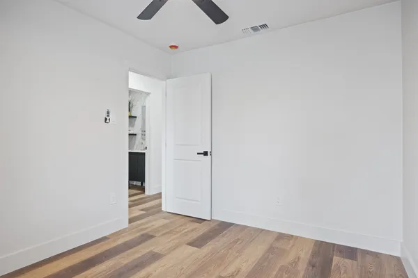 an empty room with wooden floor closet and windows