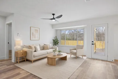 a living room with furniture a large window and wooden floor