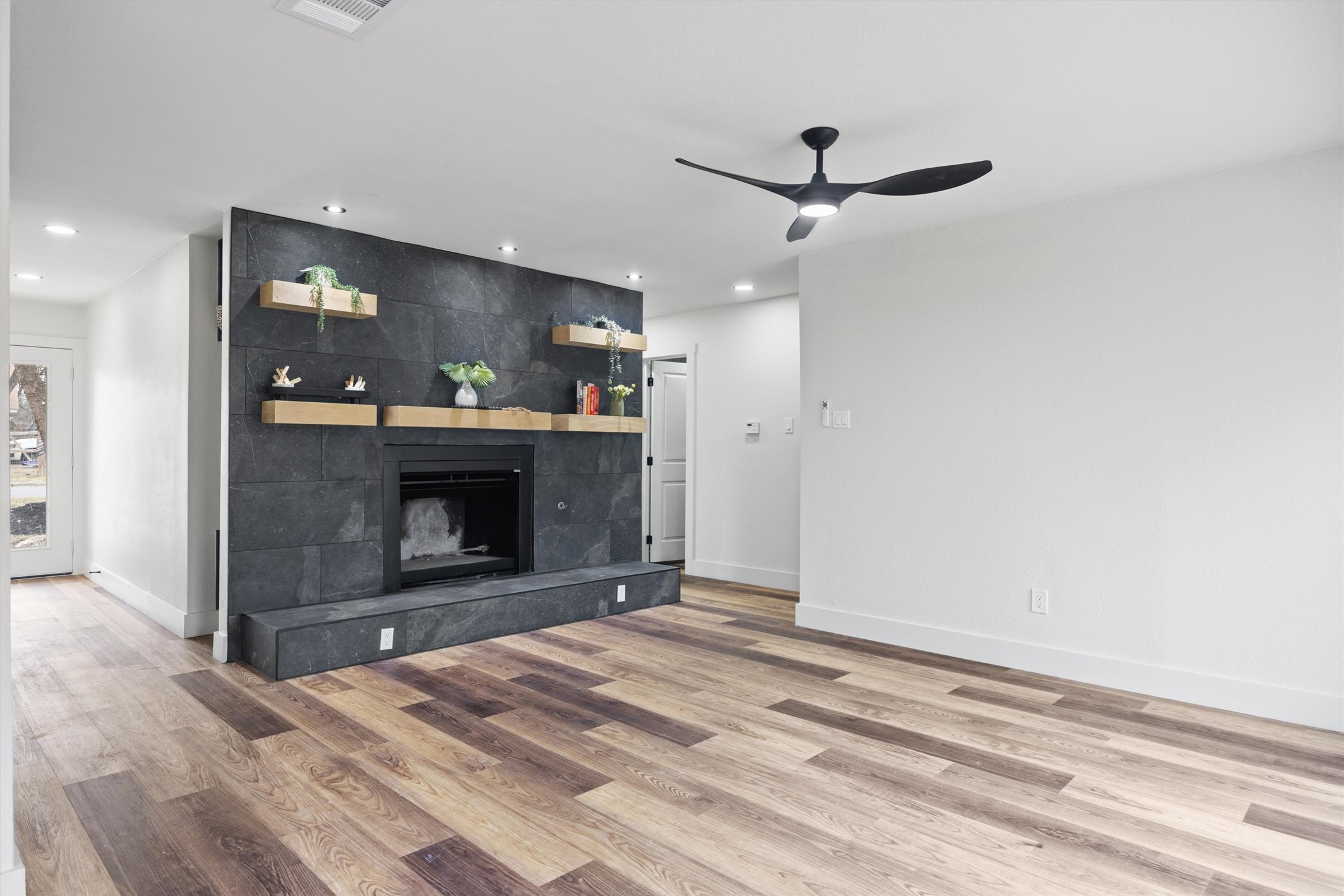 6212 Boxcar Run Austin, TX 78745 - Photo 9 of 36 Unfurnished living room featuring ceiling fan, light wood finished floors, a tiled fireplace, and recessed lighting