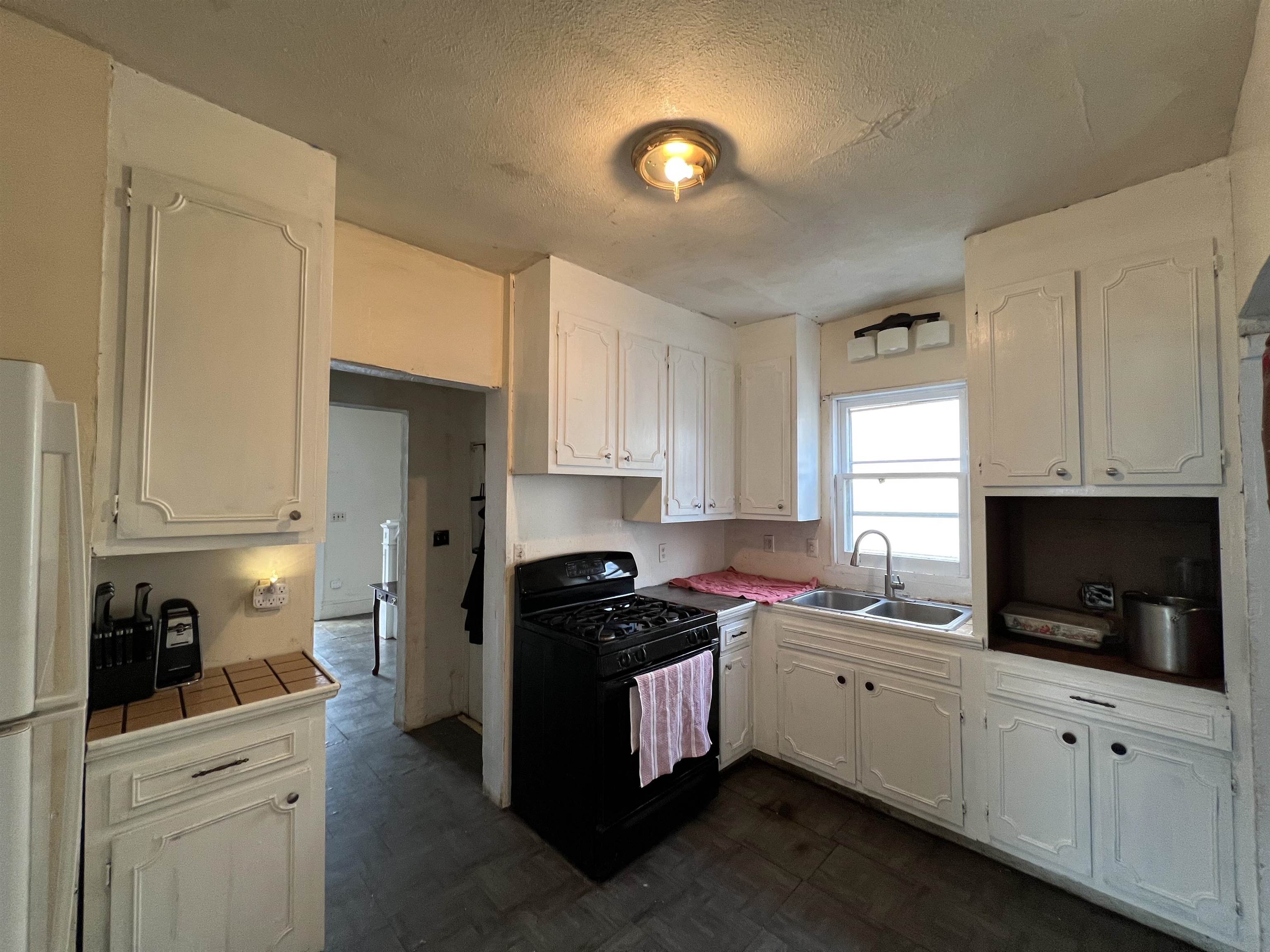 220 Elizabeth Avenue Waynesboro, VA 22980 - Photo 9 of 16 a kitchen with stainless steel appliances white cabinets a sink a stove a refrigerator and microwave with wooden floor
