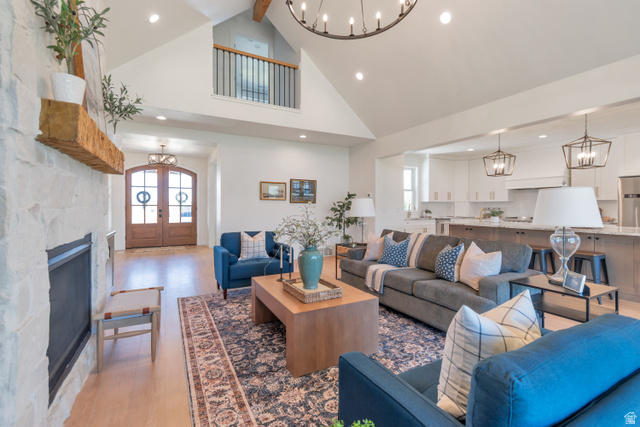 1820 West Farmhouse Flats Road Peoa, UT 84061 - Photo 14 of 79 Vaulted living space featuring a stone fireplace with a substantial wood mantel, light wood-finish flooring, and an overhead chandelier