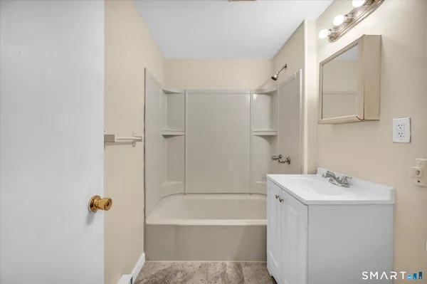 a bathroom with a tub sink shower and mirror
