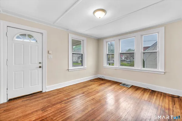 a view of an empty room with wooden floor and a window