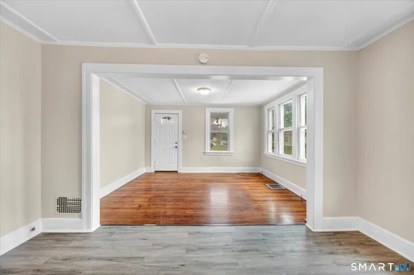 a view of an empty room with wooden floor and a window