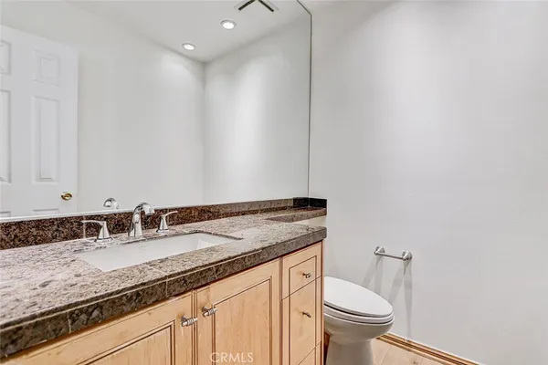 a bathroom with a granite countertop sink a toilet and a mirror