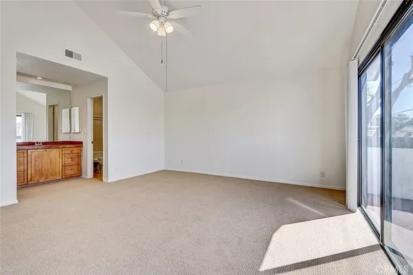 an empty room with chandelier fan and windows