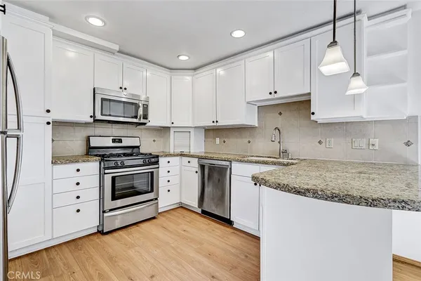 a kitchen with stainless steel appliances granite countertop a sink a stove a microwave and cabinets