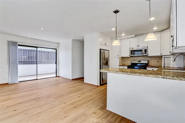 a large kitchen with stainless steel appliances granite countertop a stove a refrigerator a oven and a wooden floors