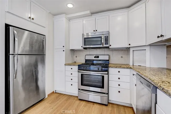 a kitchen with stainless steel appliances white cabinets and a refrigerator