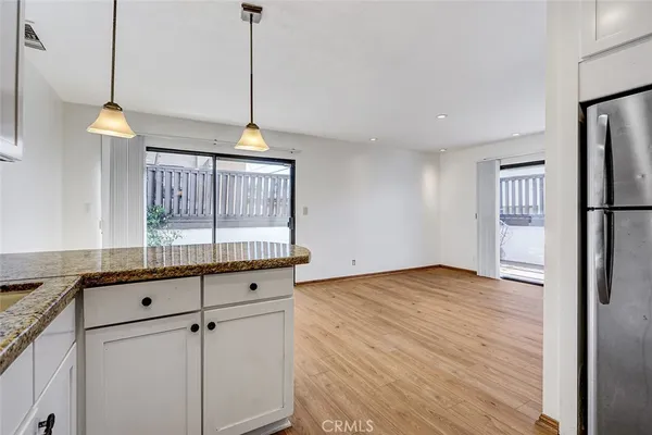 a kitchen with granite countertop a refrigerator a sink and a chandelier