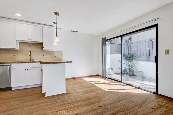 a kitchen with granite countertop a stove a sink and white cabinets with wooden floor